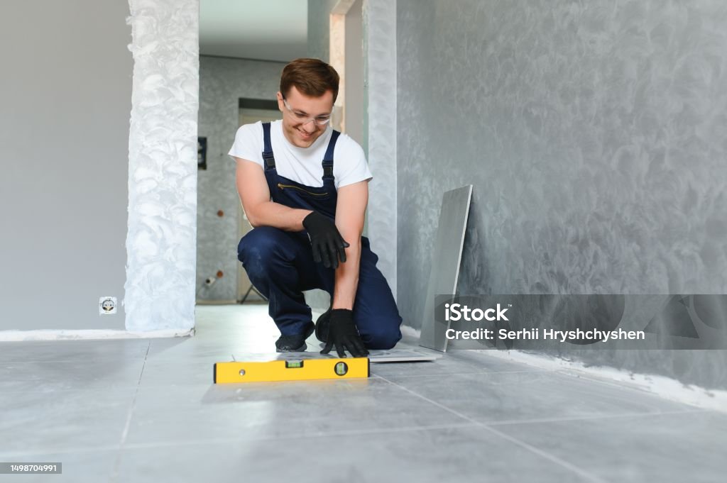 Industriearbeiter, Handwerker beim Verlegen großer Keramikfliesen.